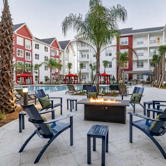 A patio with chairs and a fire pit in front of a building.