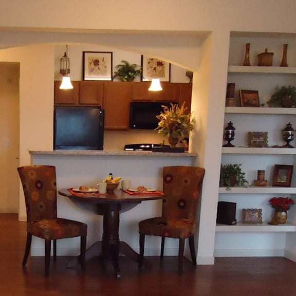 A dining room with a table set for two and a television.