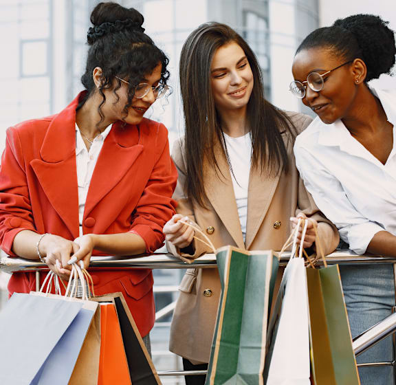 Three women with shopping bags on a city street.