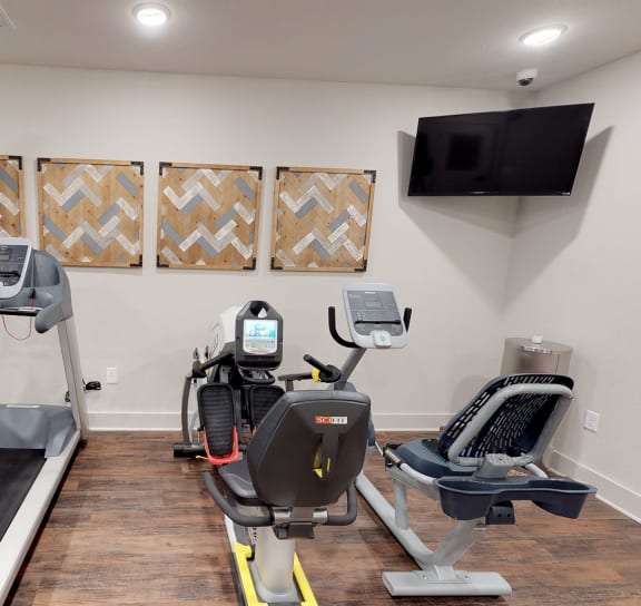 a room with two treadmills and two televisions