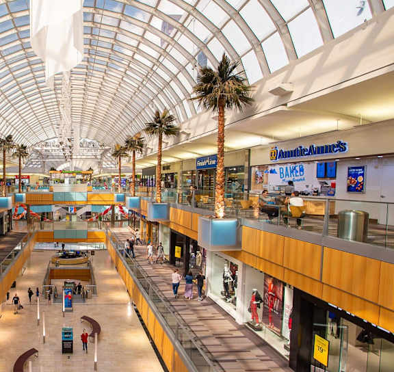 A large atrium with a glass roof and people walking around.