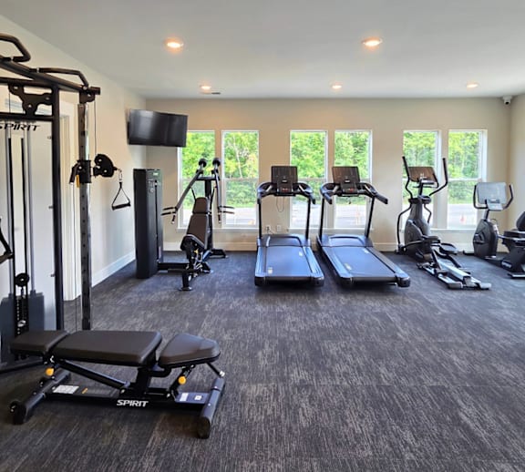 A spacious gym with a variety of equipment including treadmills, stationary bikes, and weight machines.