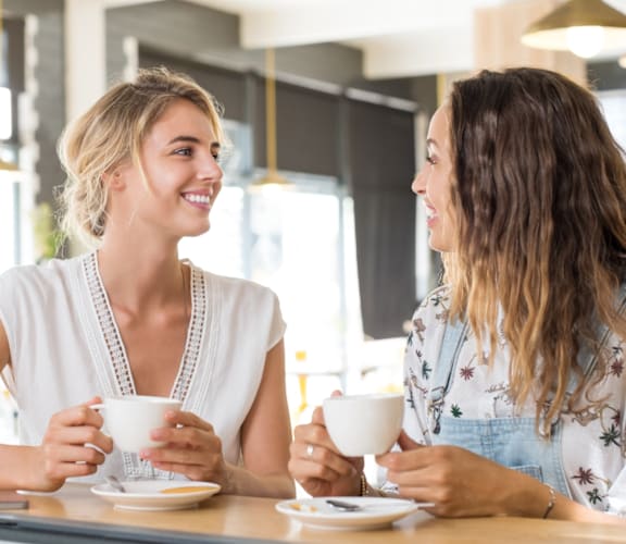 Two women having a conversation over a cup of coffee in a cafe.