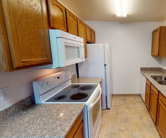 A kitchen with a stove and a sink and a refrigerator at Amber Ridge Apartments. 