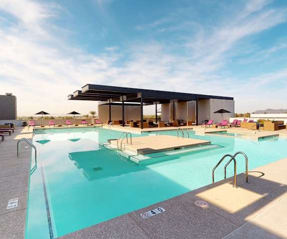 The turquoise rooftop pool with an island in the middle surrounded by purple pool chairs and black umbrellas at the Trend at 51 Apartment Homes. 