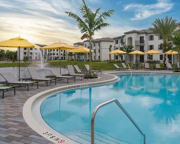a large swimming pool with umbrellas in front of a hotel