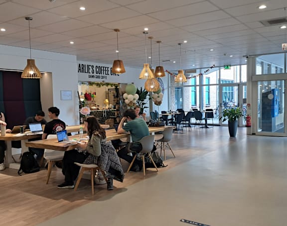 A group of people are sitting at tables in a large open space.