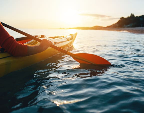 A person is kayaking on the water during sunset at Rosemeade Apartments, Roseville, CA 95661