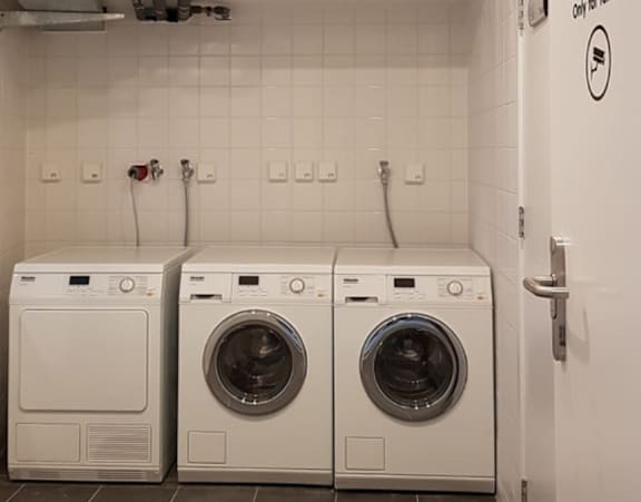Two front loading washing machines in a small laundry room.