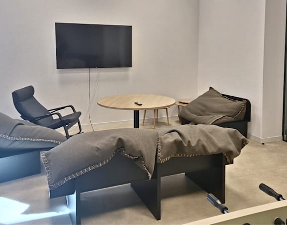 A modern lounge area with a television, chairs, and a table.