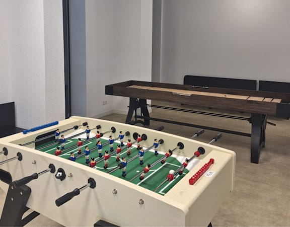 A foosball table is in a room with a bench.