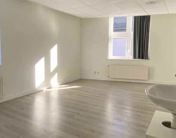 A white bathroom with a window and a radiator.