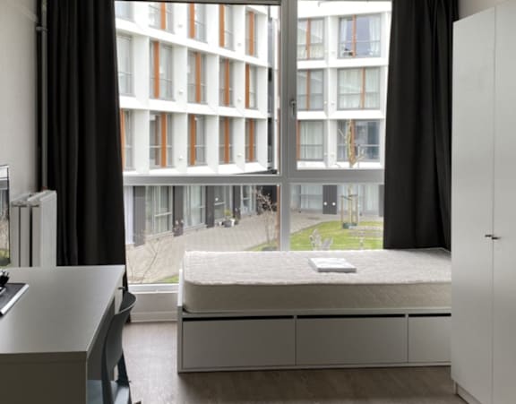 a bedroom with a bed and a desk and a window