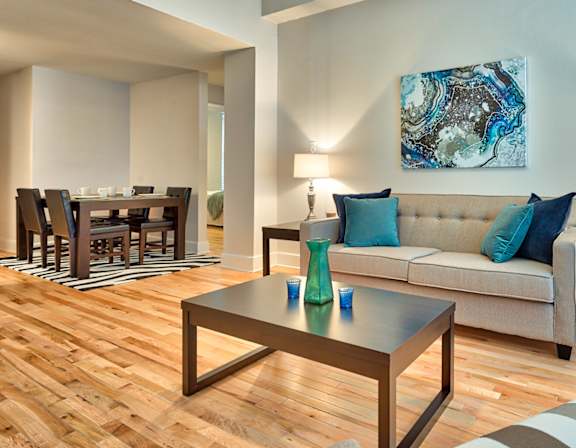 A living room with a couch, coffee table, and a painting on the wall.
