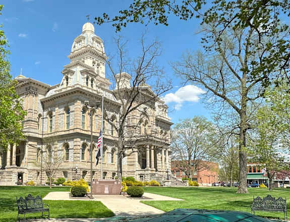 A large, ornate building with a clock tower sits in the middle of a park.