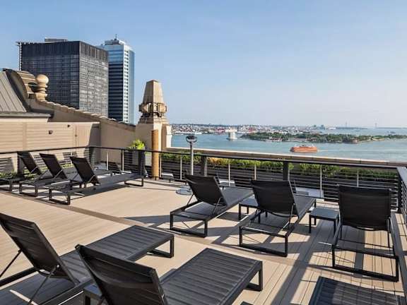 A balcony with black chairs and a view of the city. at One West,New York, NY
