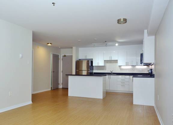 A kitchen with white cabinets and a wooden floor.