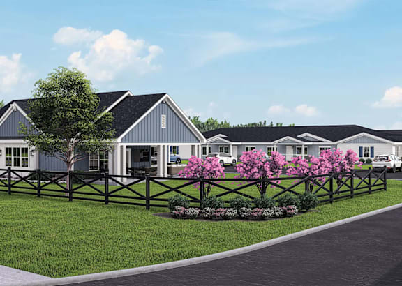 A row of houses with a fence and flowering bushes in front.