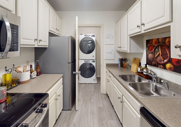 a kitchen with a sink and a refrigerator and a washing machine at The Bosk Apartment Homes, Woodbury, MN