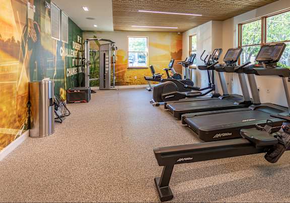 a room with a row of treadmills and a wall with a painting of a soccer