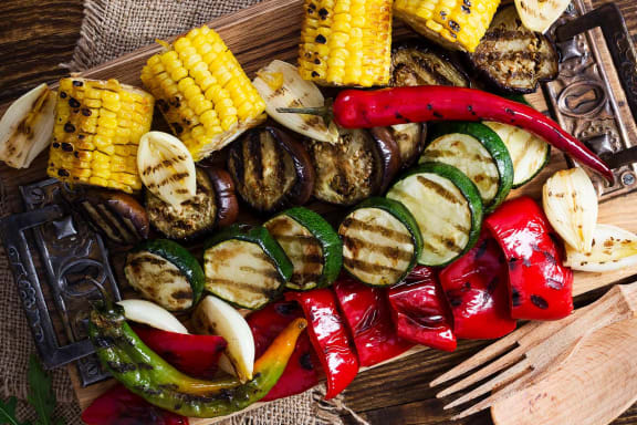 skewers of grilled vegetables on a cutting board with a fork
