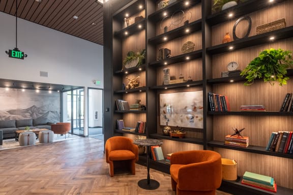 a view of the lobby with a large bookshelf in the background and orange chairs in