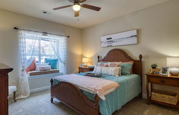 A bedroom with a bed, nightstand, and window.