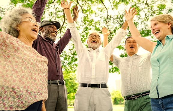 A group of people are standing together with their arms raised.