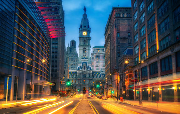 a city street at night with a clock tower in the background