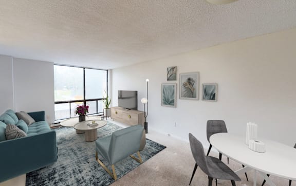 A living room with a grey couch, a white table, and a blue rug.