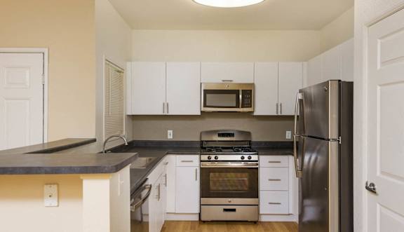 A kitchen with white cabinets and a black countertop.