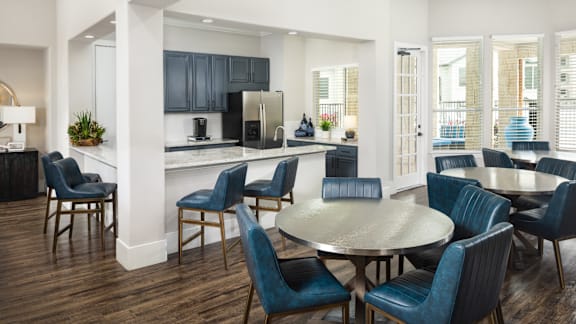 A modern kitchen with dark blue chairs and a wooden table.