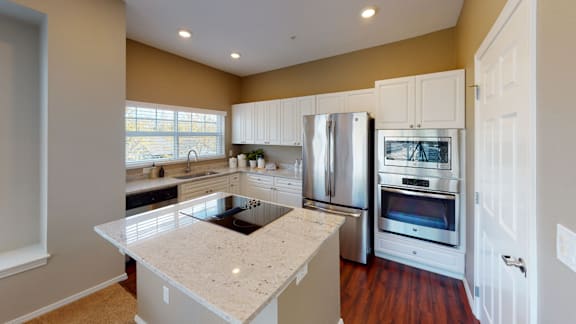 A kitchen with a white island and stainless steel appliances.