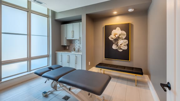 A room with a massage table and a picture of a flower on the wall.