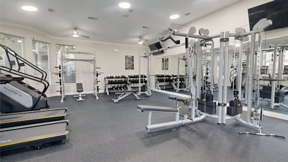 A gym with a variety of equipment including treadmills, weights, and machines.