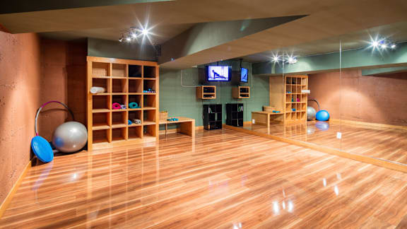 A gym with wooden floors and exercise equipment.