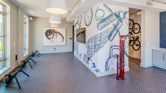 A room with a mural of bicycles and a clock on the wall.