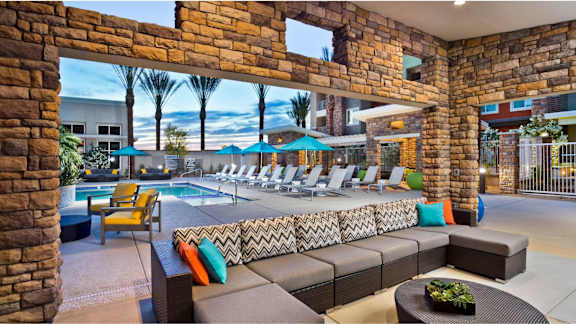 A patio with a pool and lounge chairs.
