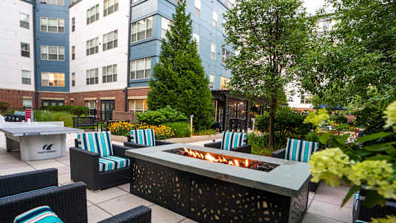 A patio with a fire pit and chairs.