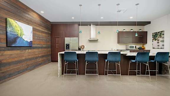 A modern kitchen with a bar area and chairs.
