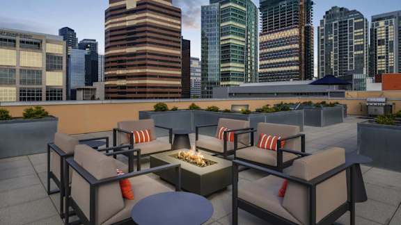 A patio with a table and chairs overlooking a city skyline.