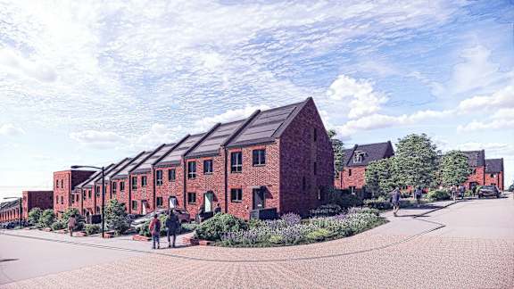 A red brick building with a black roof and a few people walking around.
