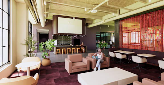 A woman is sitting on a chair in a room with a bar and a large window. at University Commons in Pittsburgh, PA