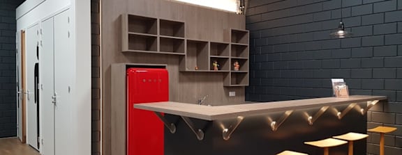 A modern kitchen with a red fridge and wooden cabinets.