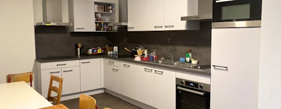 A modern kitchen with white cabinets and a wooden table.