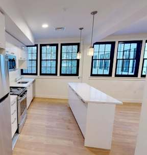 Bright kitchen with white island and black framed windows at The Overlook Apartments, Weymouth, MA 02188