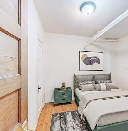 A bedroom with a bed, nightstand, and a painting on the wall.