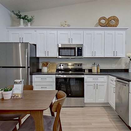 A kitchen with a table and chairs in front of it.