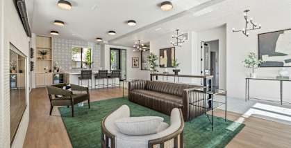 A modern living room with a green rug and a brown leather sofa.
