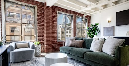 a living room with a green couch and a brick wall